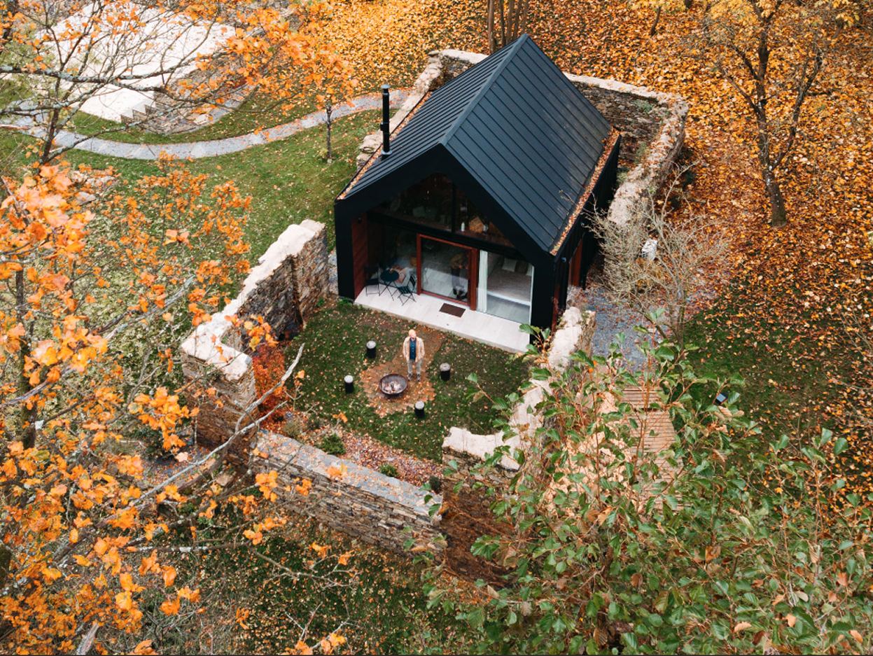 Černá A-frame dřevostavba v podzimní krajině